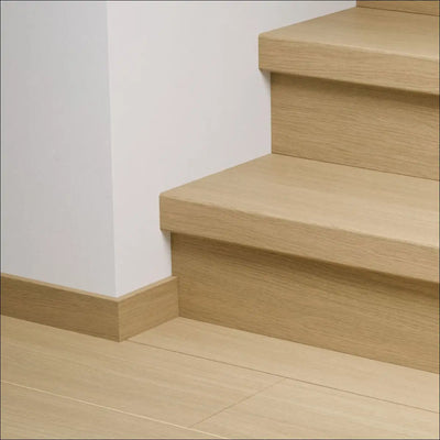 Light oak quick-step capture stair cover with minimalist wooden stair nosing and matching baseboard for stairs