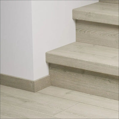 Modern light gray wooden quick-step capture stair cover with visible grain texture and matching baseboard stair nosing