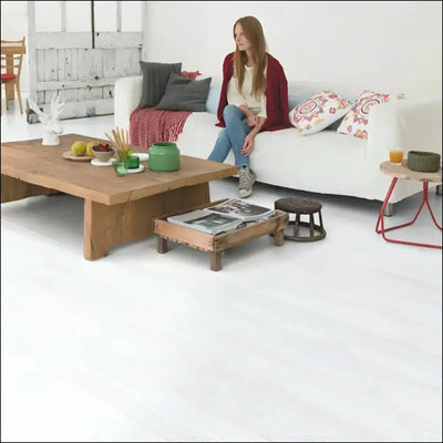 White sofa with gray and patterned pillows on quick step impressive laminate flooring in white planks