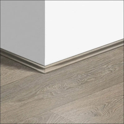 Gray wood-grain laminate quickstep classic scotia beading baseboard with subtle metallic edge for quick-step flooring