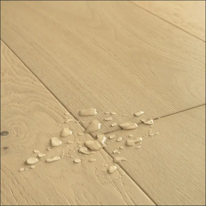 Beige quick-step cala pearl white oak extra matt flooring with water droplets on the surface