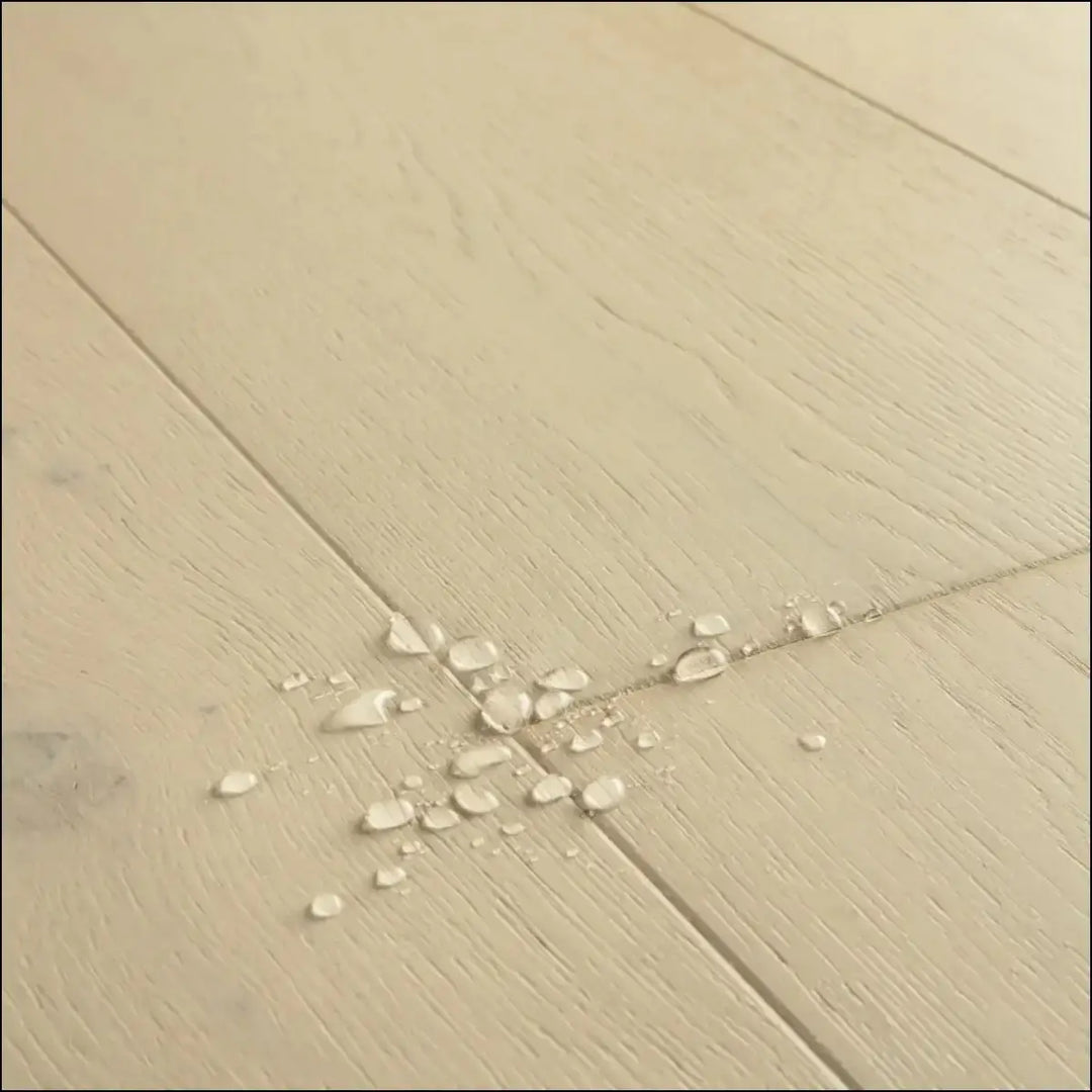 Beige wood-plank flooring with subtle grain and water droplets in quick-step cala wintry forest oak extra matt finish