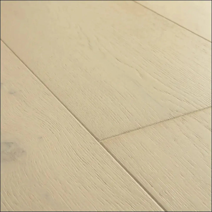 Beige quick-step cala wintry forest oak hardwood flooring with subtle wood grain texture and natural-looking knots