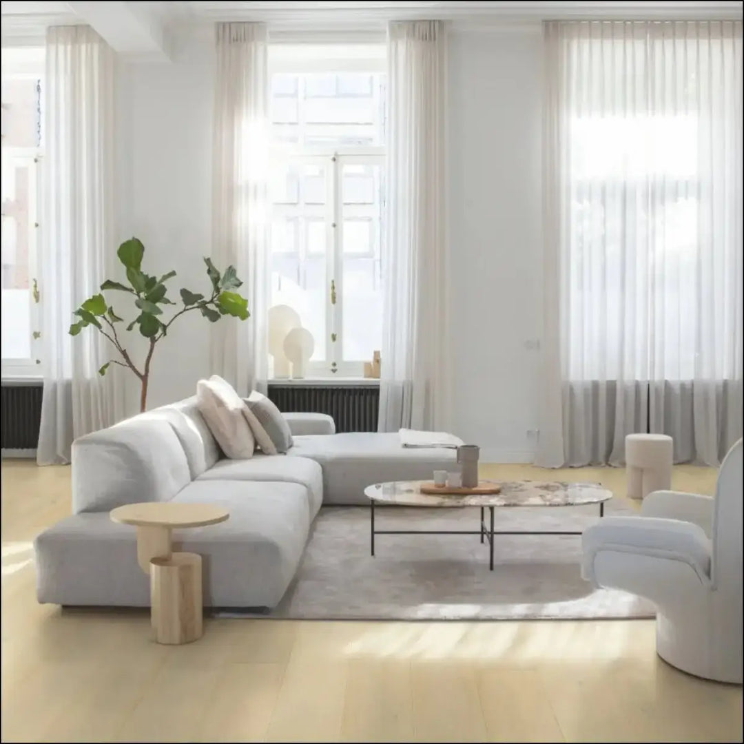 Light gray sectional sofa with plush cushions and minimalist design in quick-step cala wintry forest oak extra matt finish