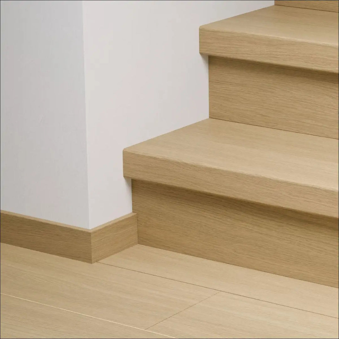 Light oak quick-step capture stair cover with minimalist wooden stair nosing and matching baseboard for stairs