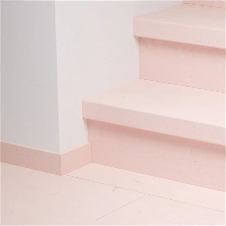 Pastel pink quick step capture stair cover on wooden staircase with matching baseboard and stair nosing installed