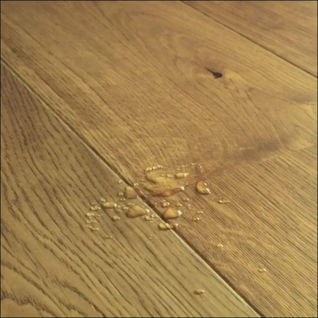 A puddle of clear liquid on quick step cascada wood flooring toffee brown oak with warm tone and extra matt finish