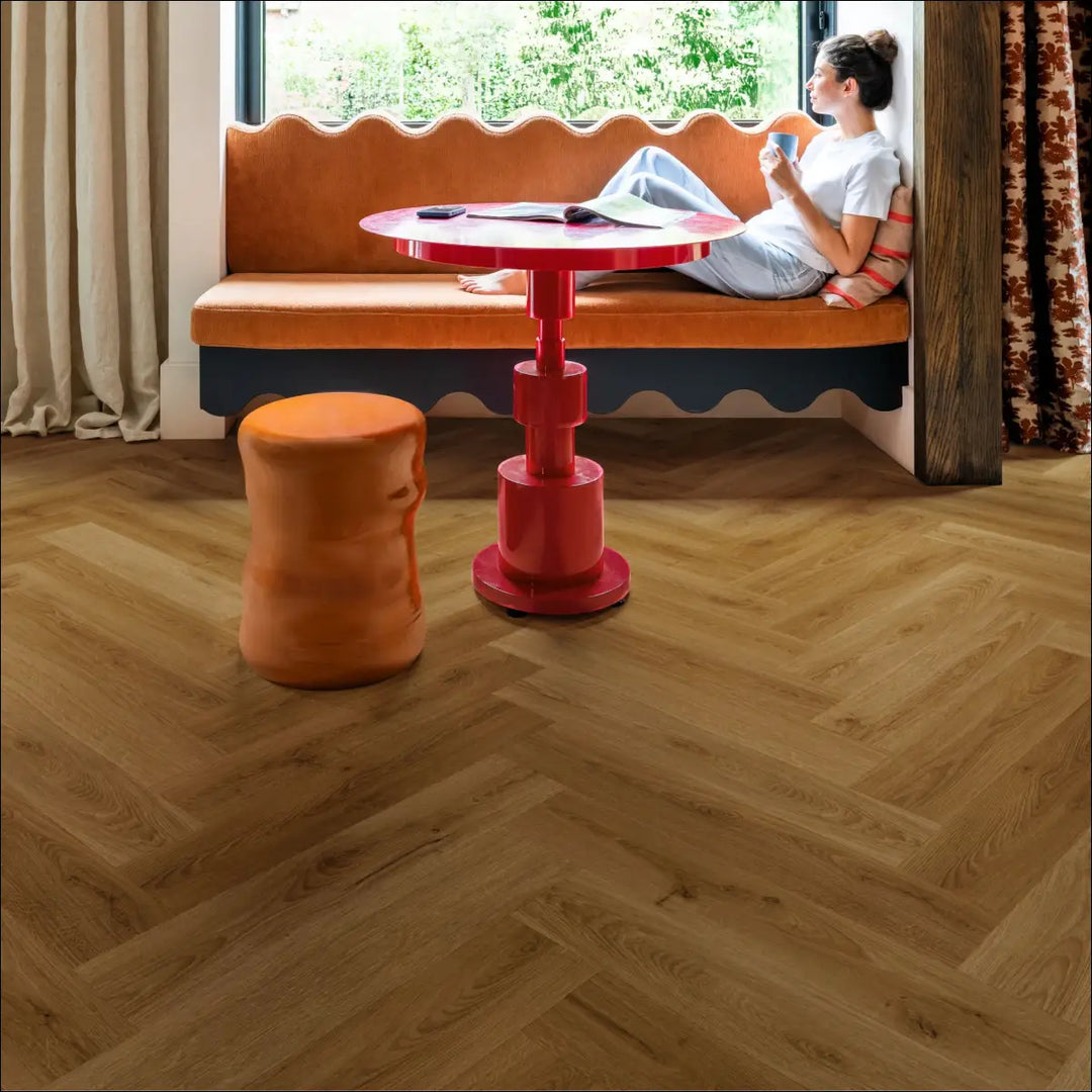 Quick Step Ciro Botanic Caramel Oak Herringbone Flooring AVHBU40364 Lounge Close Up with Lady Drinking Tea on orange Sofa