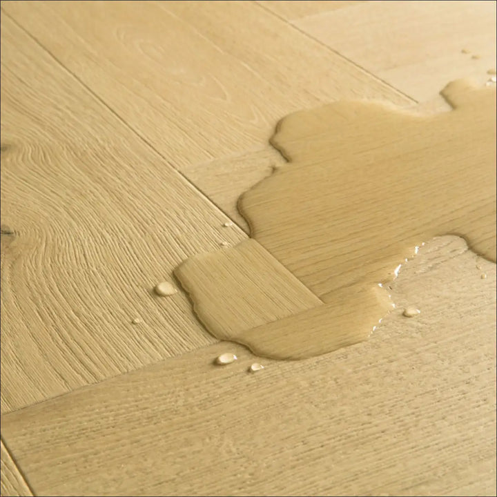 A puddle of clear liquid on light nutmeg oak imd8243 herringbone laminate flooring with scratch guard protection
