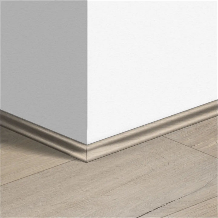 Silver-toned quickstep impressive scotia baseboard with sleek curved profile along light gray wall and wooden floor