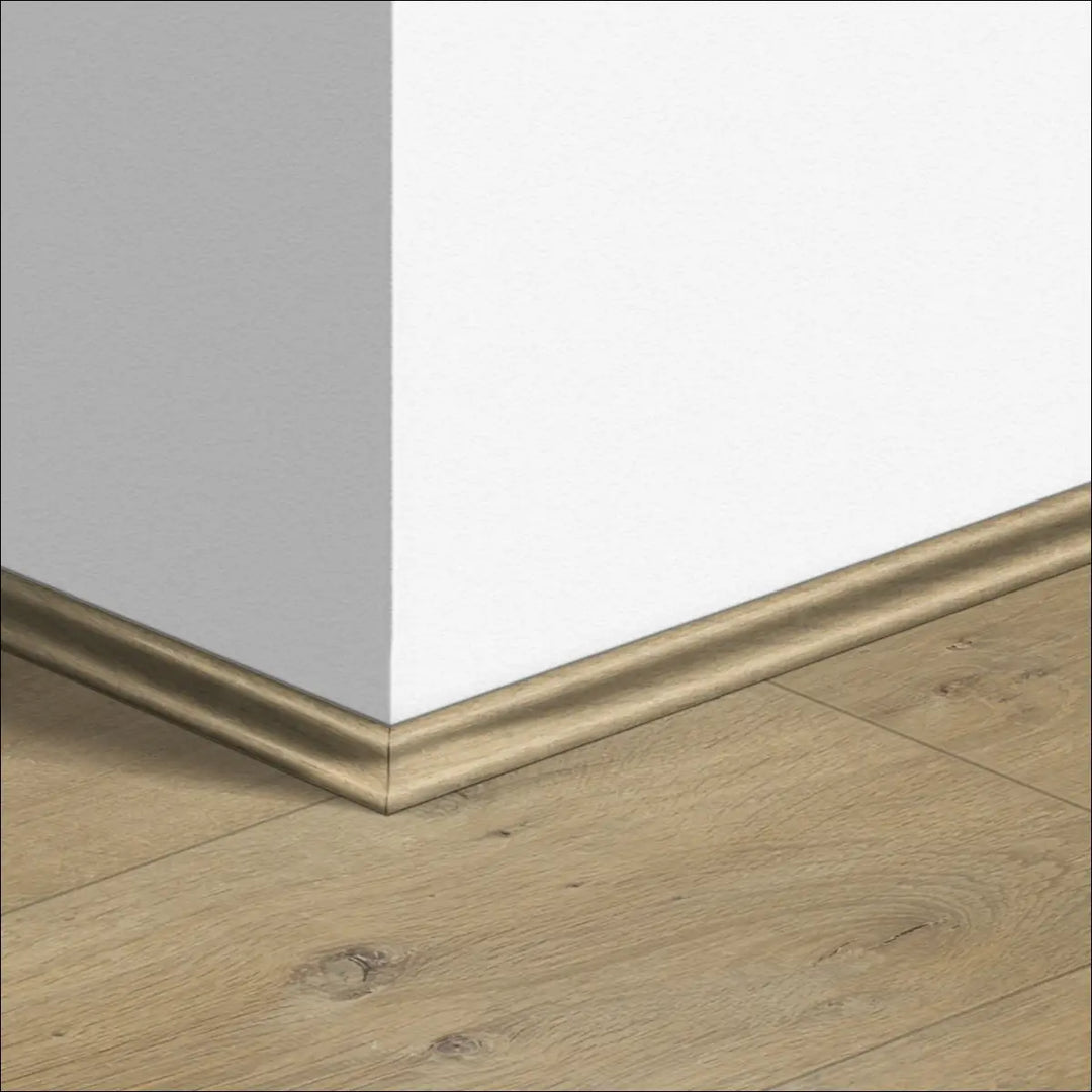 Gold-toned quickstep impressive scotia baseboard with matte finish along gray and white walls and wooden flooring