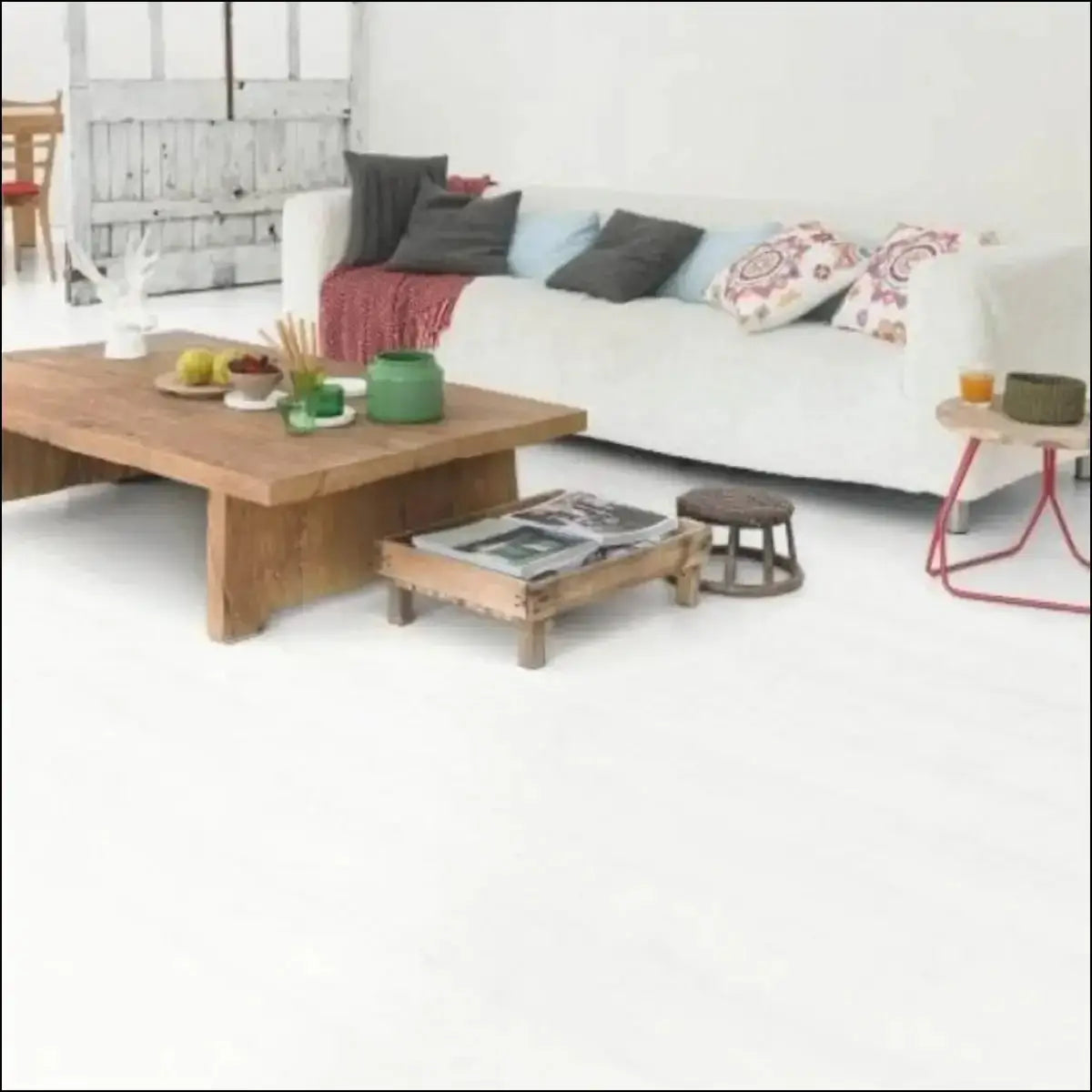 White sofa with dark gray and patterned throw pillows on quick-step impressive ultra white laminate planks
