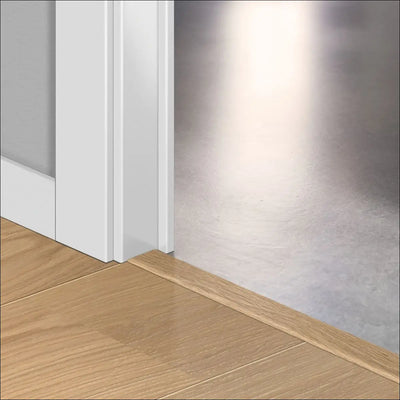 White door threshold with wood grain finish blending into floor and trim featuring quickstep cala incizo stair nosing profile