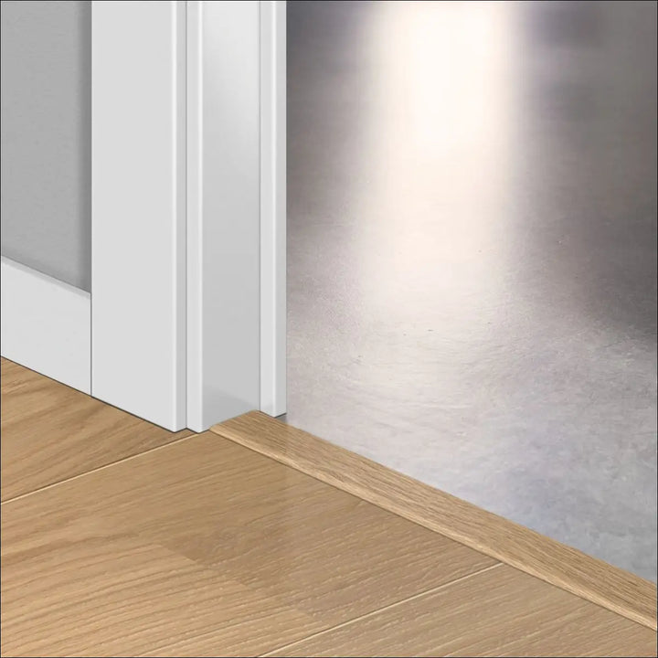 White door threshold with wood grain finish blending into floor and trim featuring quickstep cala incizo stair nosing profile