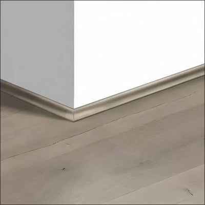 Silver metallic quickstep capture scotia baseboard trim covering expansion gaps between white wall and gray laminate flooring