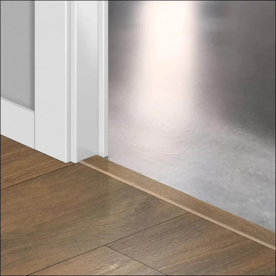 Light brown wooden floor trim with quickstep classic incizo profile used as multi-use profile by white door frame and metal wall
