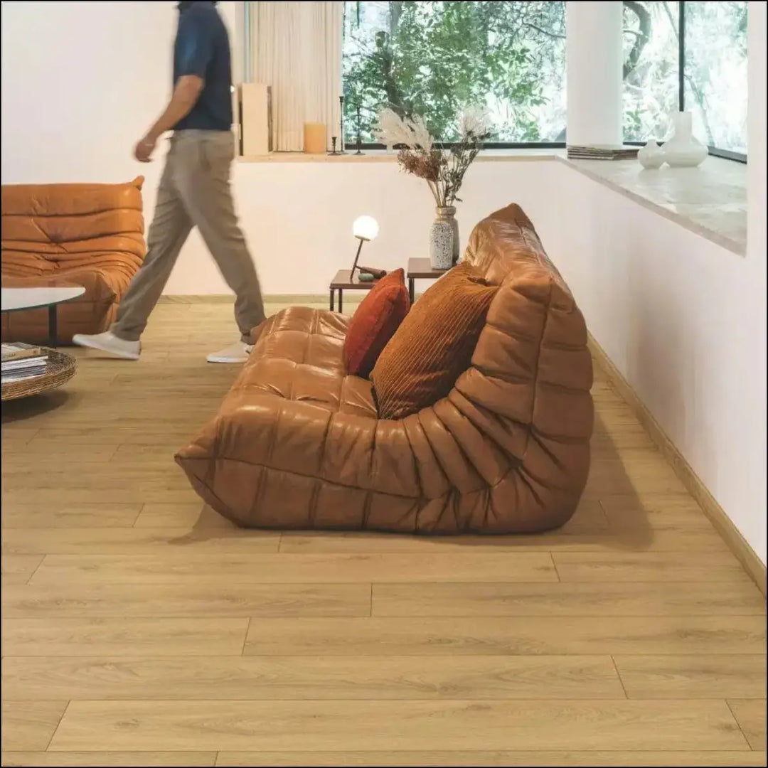 Brown leather modular sofa with tufted quilted design and plush cushions on quick-step classic laminate flooring sandy oak clm5801