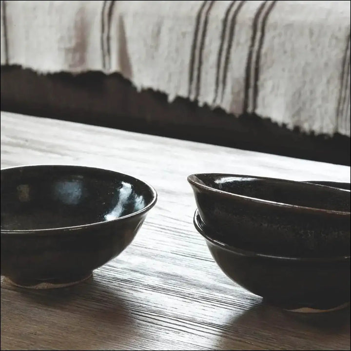 Two small glossy black ceramic bowls on quickstep classic havana oak natural laminate flooring with saw cuts
