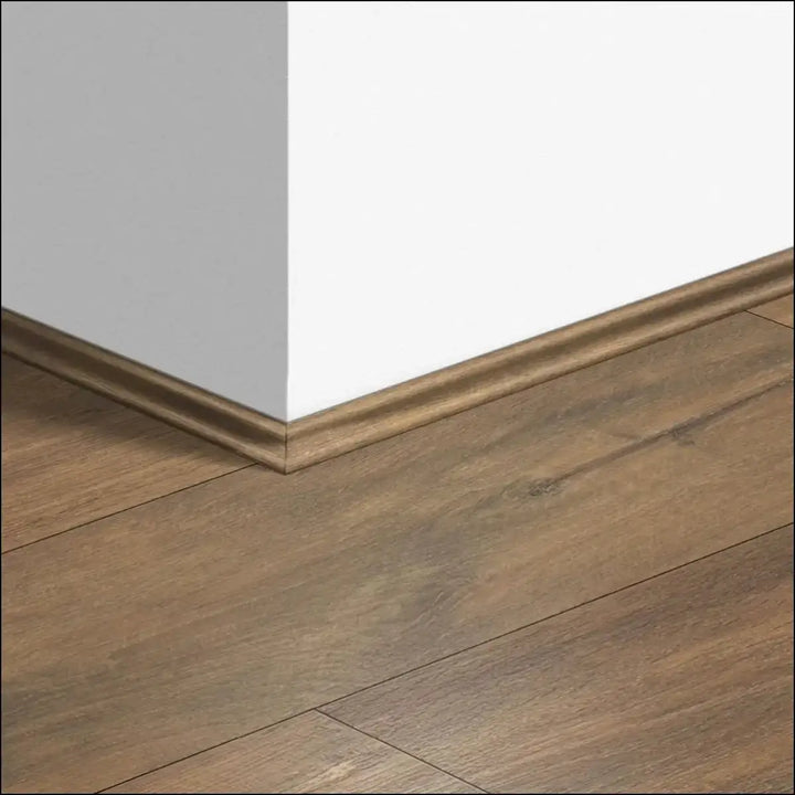 Brown wooden quickstep classic scotia beading trim with smooth glossy finish along white wall corner for quick-step flooring