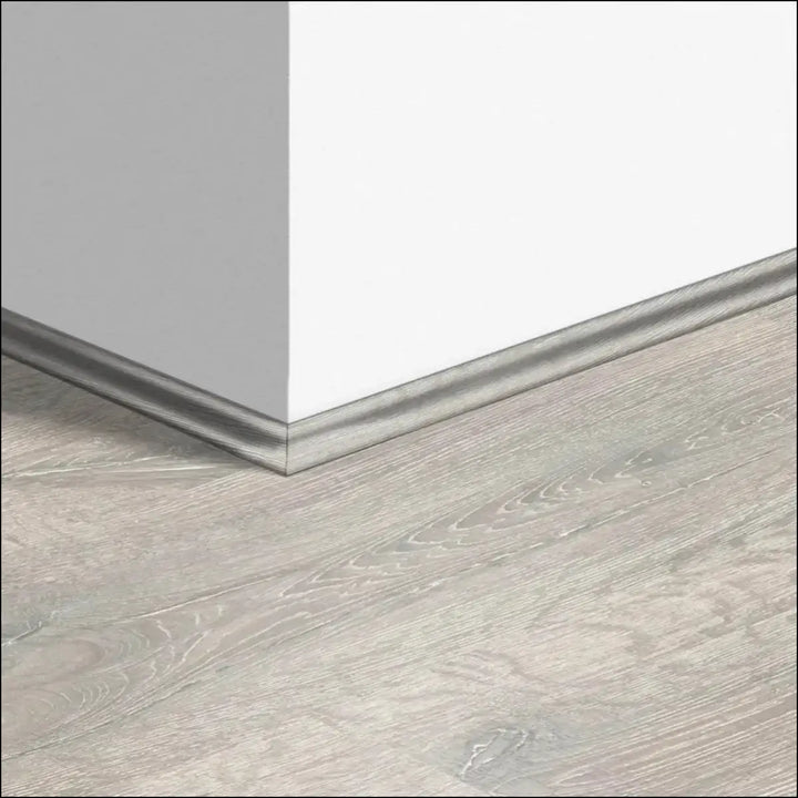 Silver metallic quickstep classic scotia beading baseboard along light gray wood-look quick-step flooring corner