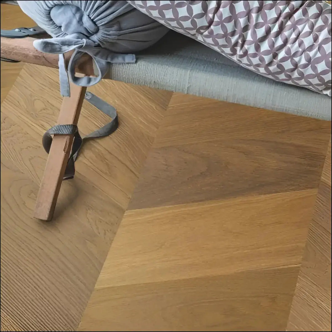 Gray fabric baby carrier with patterned cushion resting on quickstep intenso engineered wood traditional oak oiled flooring