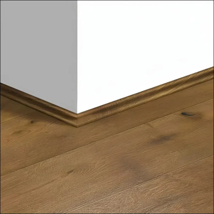 Quickstep intenso scotia warm-toned wooden baseboard with subtle grain fitting neatly between light gray and white walls