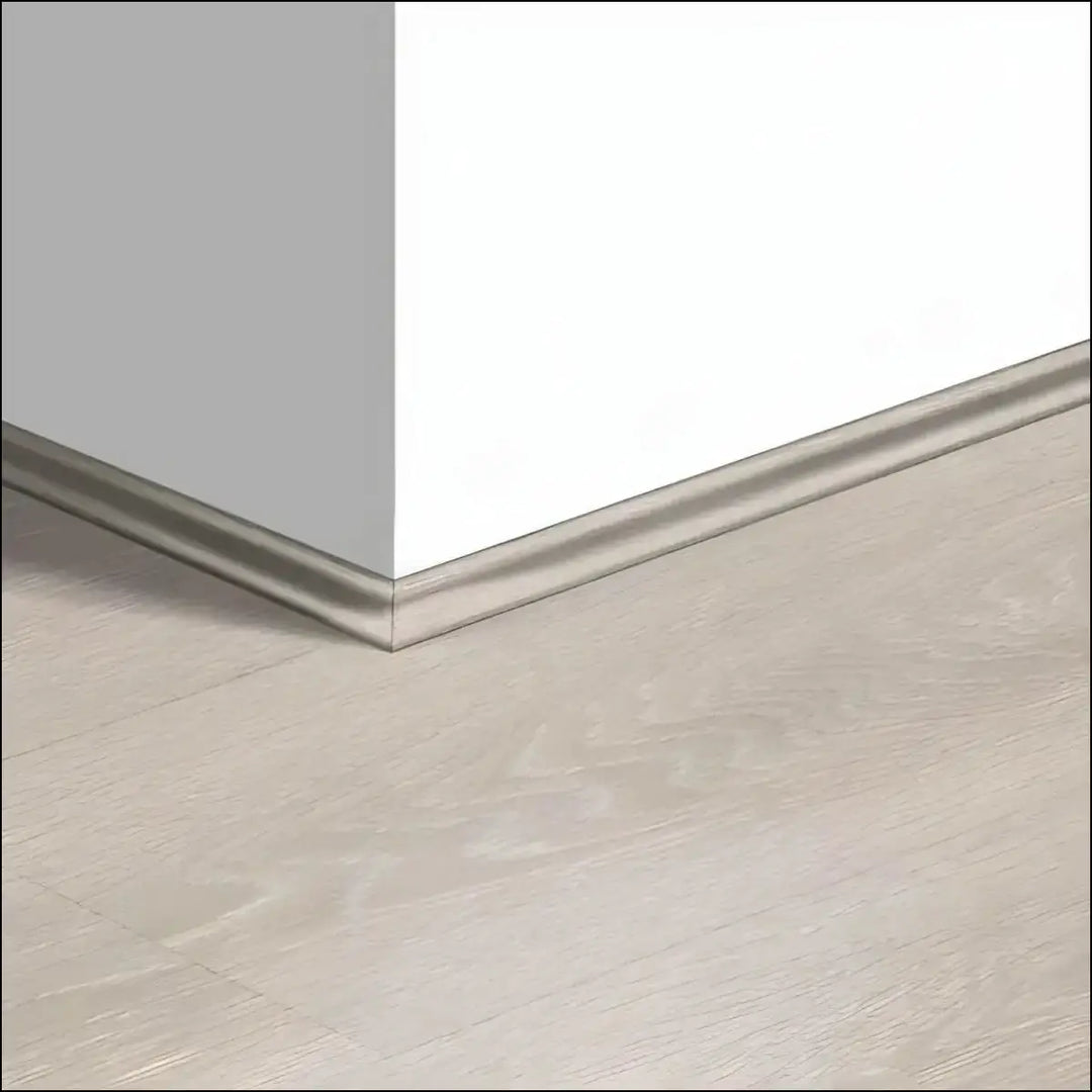 Silver metallic quickstep majestic scotia baseboard trim along white wall and light gray quick step floor corner