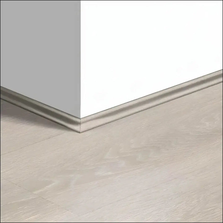 Silver metallic quickstep majestic scotia baseboard trim along white wall and light gray quick step floor corner